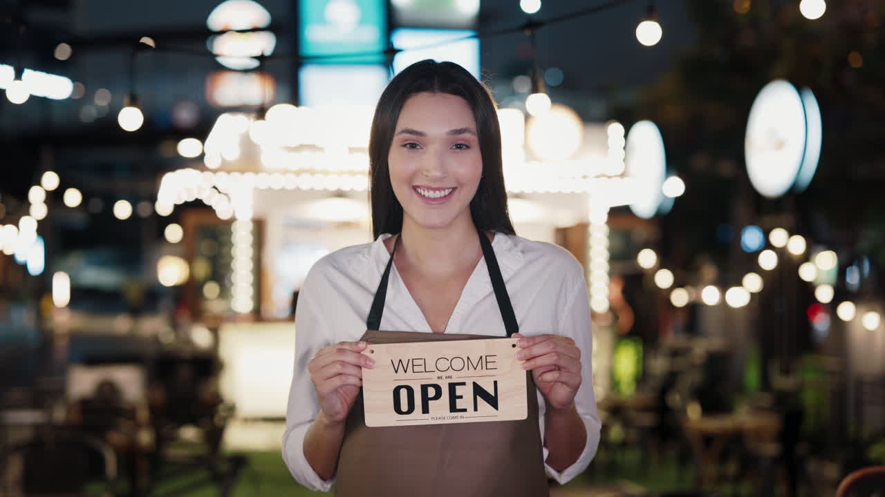 Woman holding an open sign for a cafe or restaurant at night