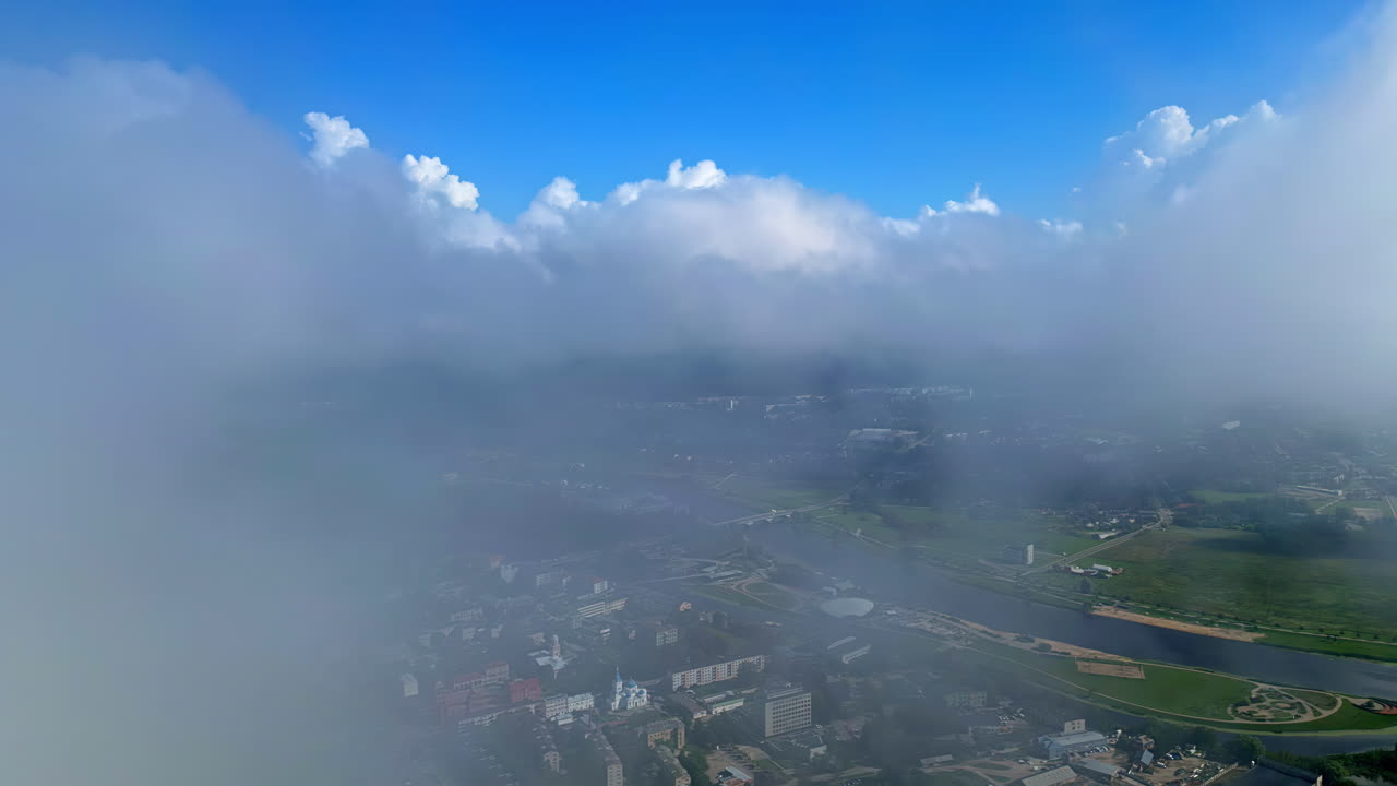 Aerial view of Jelgava city partially covered by clouds with Lielupe River in the distance
