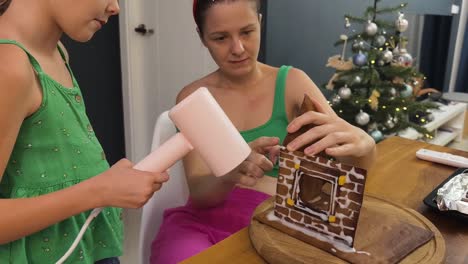 familia decorando una casa de pan de jengibre para navidad