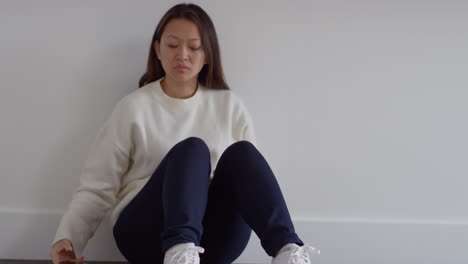 stressed or anxious woman sitting on floor at home reacting to internet or social media news message or story on mobile phone