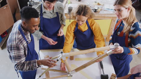 Overhead-Shot-Of-Multi-Cultural-Team-In-Workshop-Assembling-Sustainable-Bamboo-Bicycle-Frame