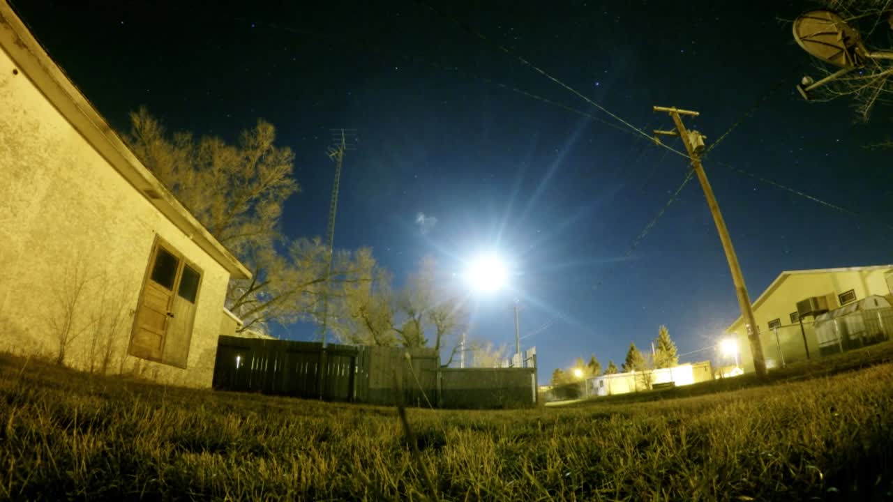 lapso de noche - vista de la luna entre casas adosadas en emperatriz alberta canada