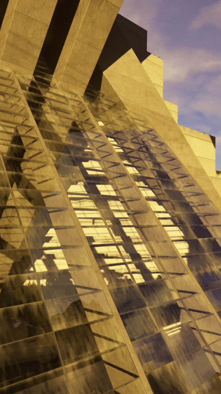 Reflexo de edifício em superfície de vidro ao pôr do sol numa área urbana.
