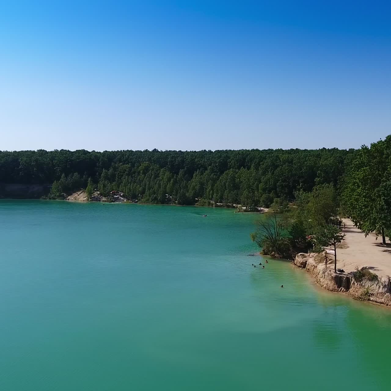 Stunning scenery of a lake made by people. Blue manmade pond at the place of former quarry and bank overgrown with trees