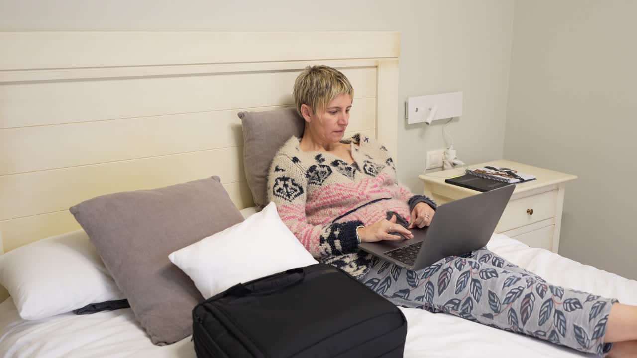 Kvinde, der arbejder på laptop i sengen
