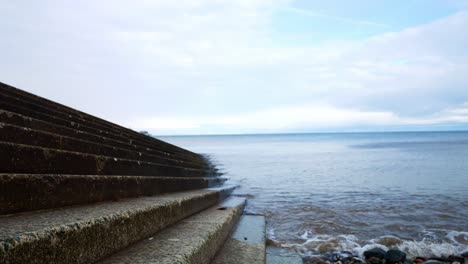 waves washing against concrete boat landing steps leading to ocean water descending right shot