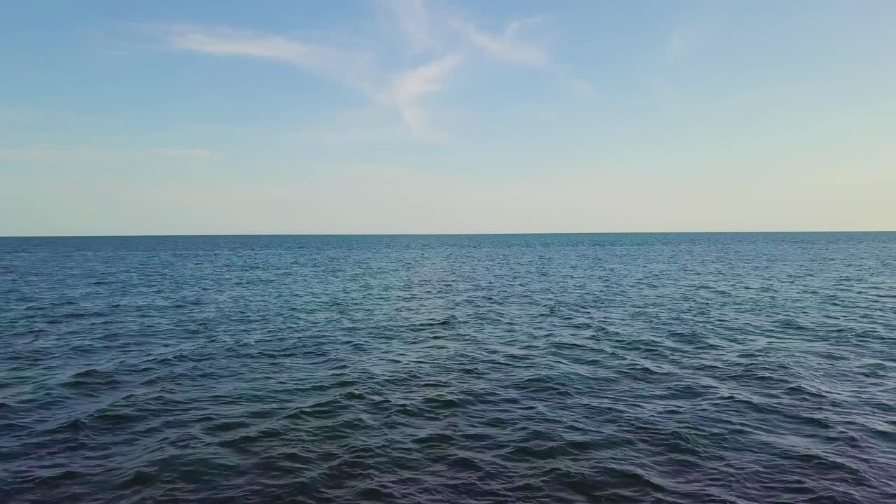 낮의 바다에서 드론이 뒤로 미끄러지는 공중 사진