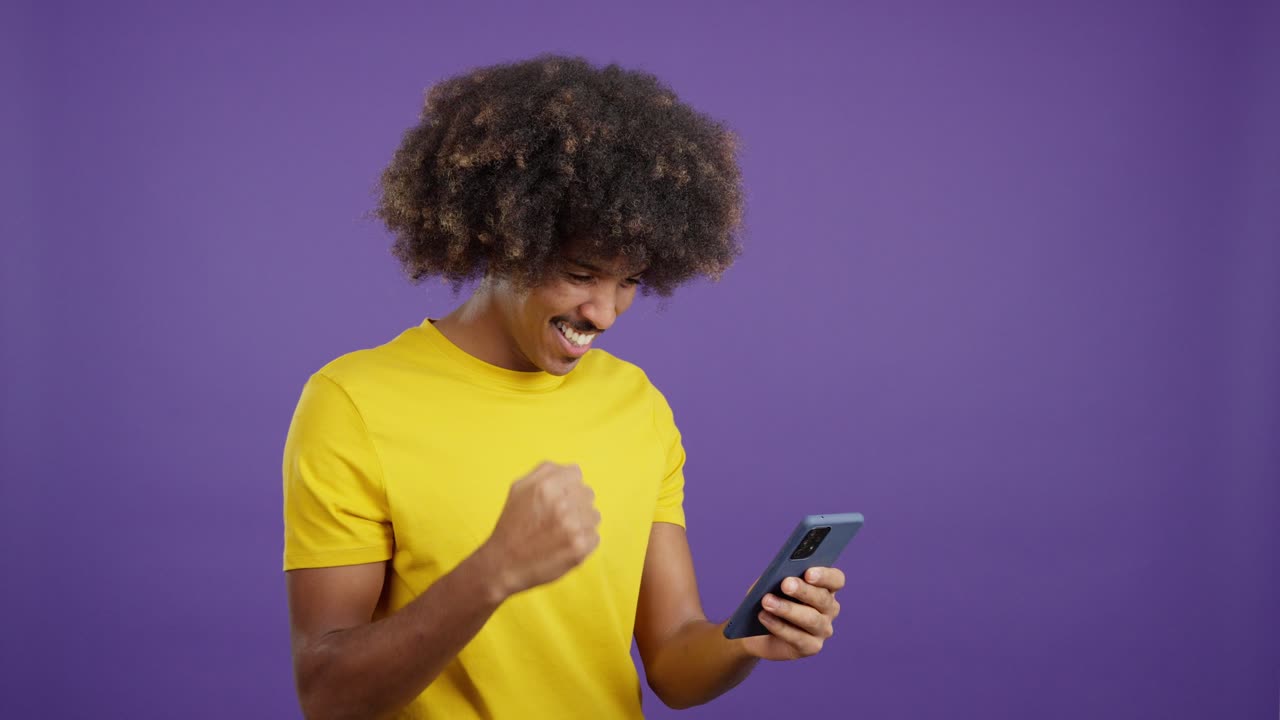 Joyful Young Man Celebrating Success with his Smartphone