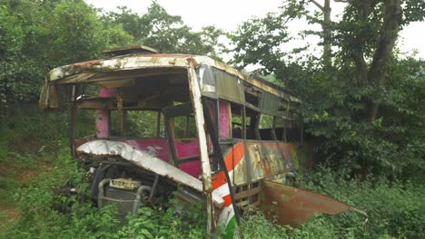 Toma-Panorámica-Derecha-De-Un-Autobús-Dañado-Y-Abandonado-Tirado-Junto-A-La-Circunvalación-De-La-Ciudad