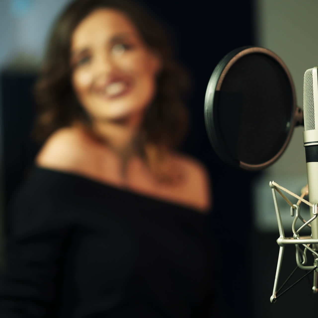 Professional condenser studio black microphone on blurred background of a woman singing. Musical equipment and a woman singer in studio