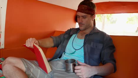 hombre leyendo una novela mientras toma café en una furgoneta 4k