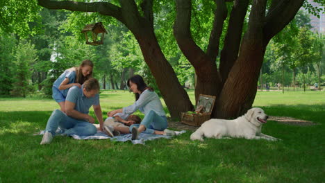 la familia riendo tiene un juego divertido en la manta de picnic. gente feliz descansando afuera.