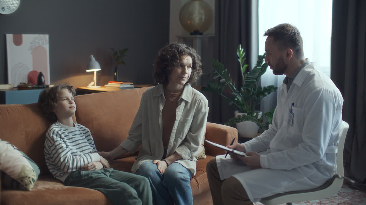 Læge konsulterer mor og sygt barn under hjemmebesøg.