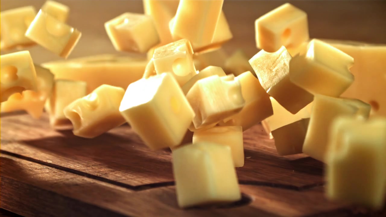 Dés de fromage tombant sur une planche à découper en bois