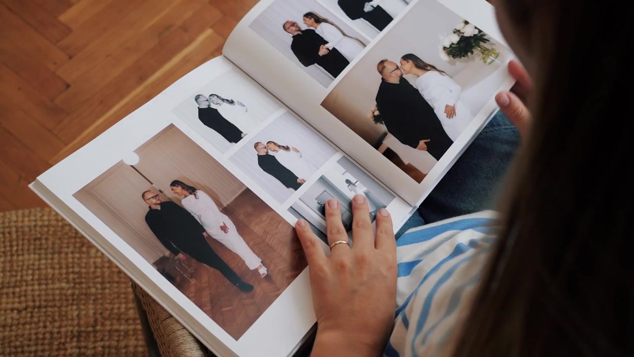 Närbild på en person i vardagskläder som långsamt bläddrar igenom ett bröllopsfotoalbum sittande inomhus