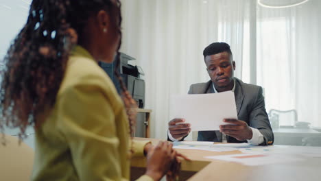 Happy-confident-black-woman-recruit-handshaking-employer-getting-hired-at-new-job.-Smiling-young-female-professional-manager-shake-hand-of-black-man-client-or-customer-making-business-office-meeting