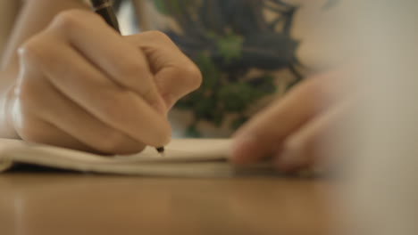 close up of hand holding a pen and writing on a notebook