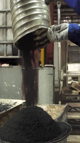 industrial process: pouring dark powder material