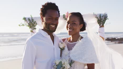 Porträt-Eines-Verliebten-Afroamerikanischen-Paares,-Das-Heiratet-Und-Am-Strand-In-Die-Kamera-Lächelt