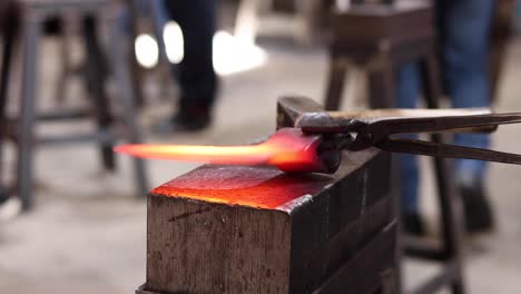 artesano con pincel de alambre y pinzas forjando hacha de metal