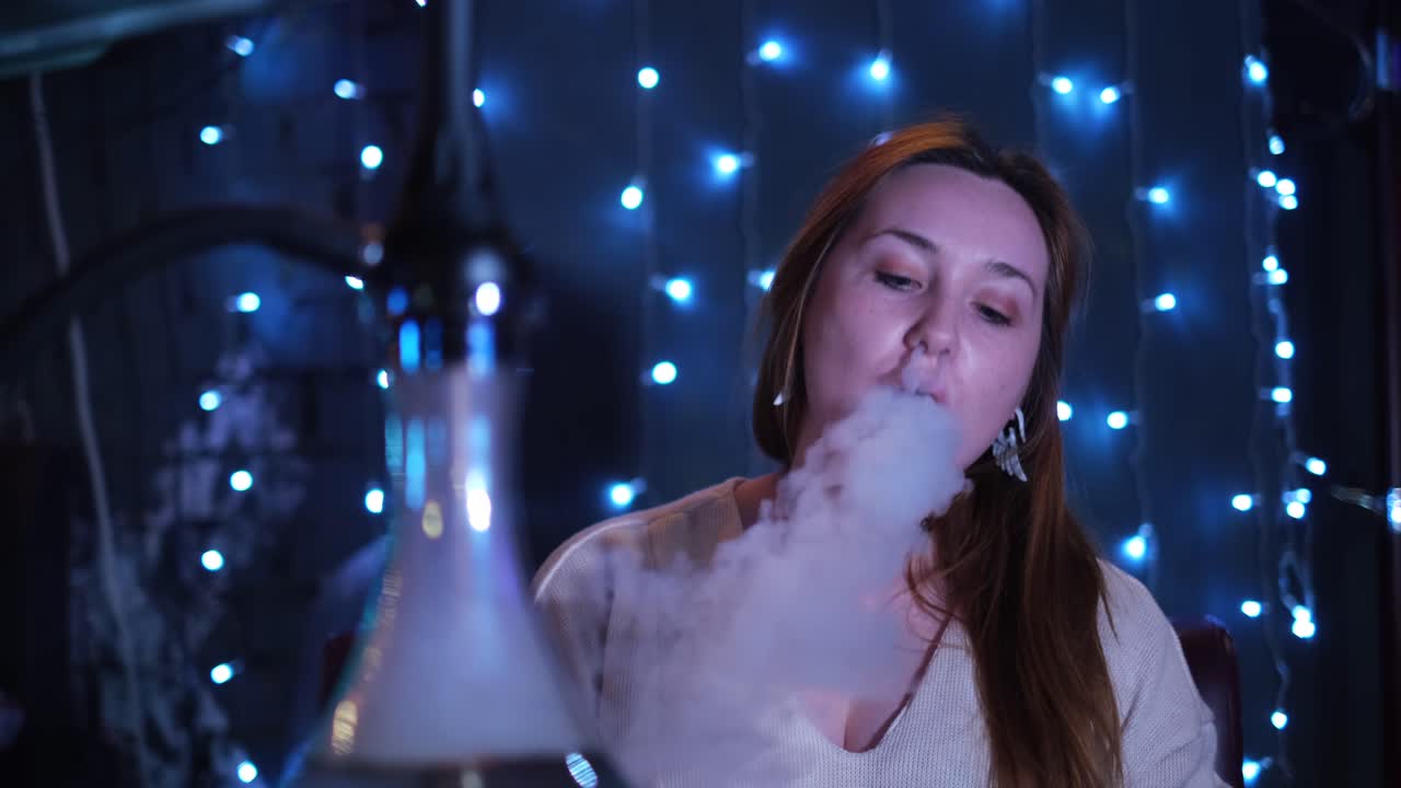 mujer fumando narguile en un club nocturno