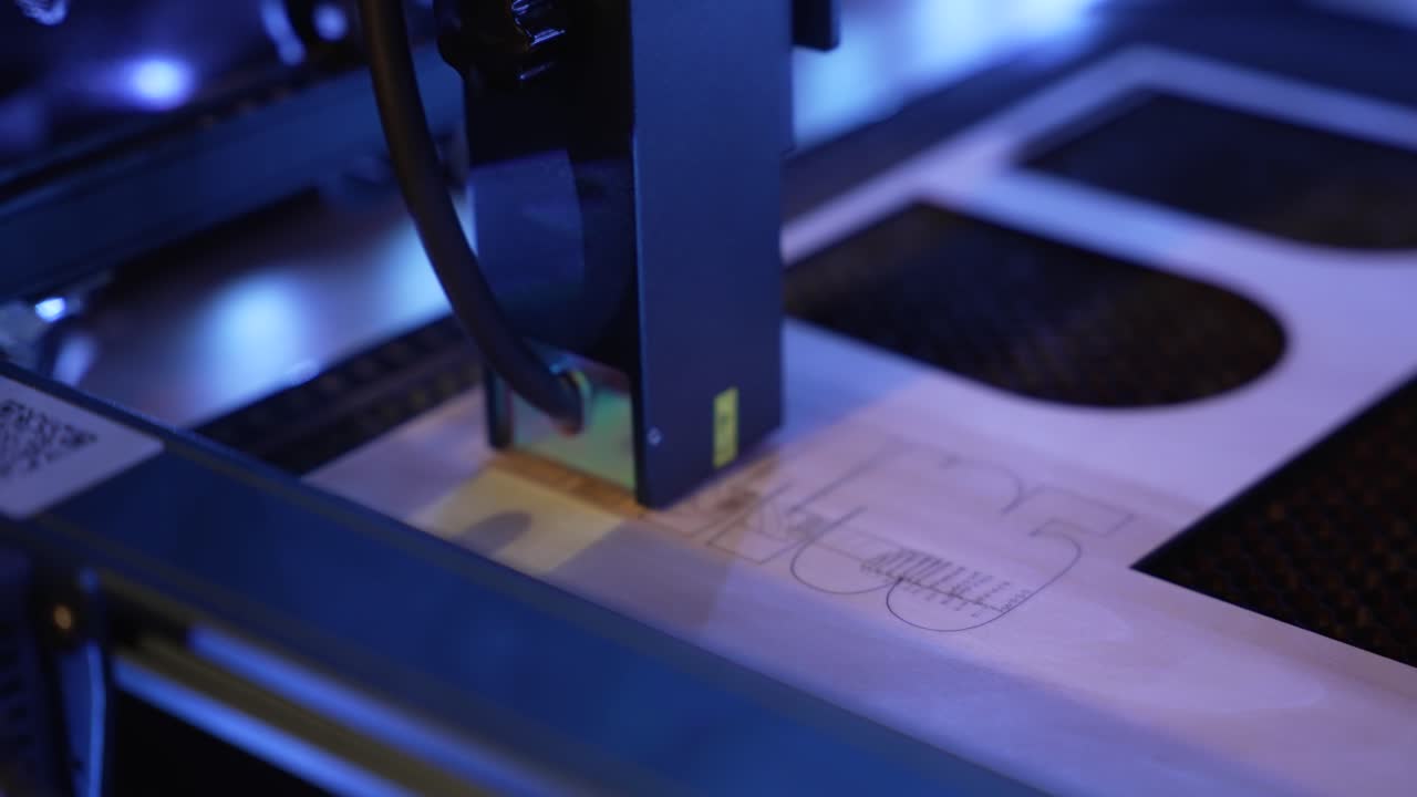 A close-up view of a laser engraver cutting wood in a blue-lit industrial setting, highlighting precision and technology