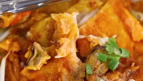 detailed view of a crispy mussel pancake topped with fresh herbs and served with utensils.