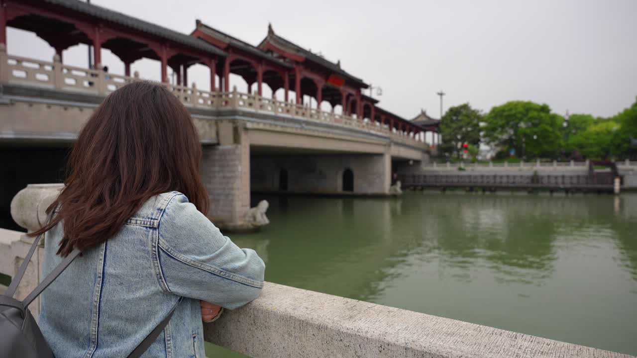 Donna che osserva il Ponte Pingmen e il canale sottostante a Suzhou, Cina. Ripresa a mano libera