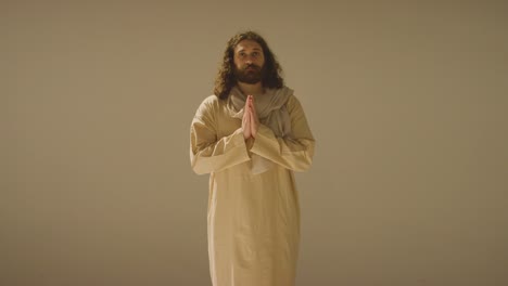 retrato de un hombre con cabello largo y barba que representa la figura de jesucristo poniendo las manos juntas en oración 1