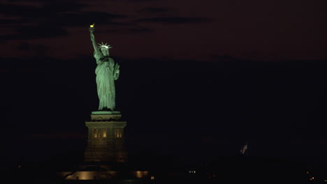 statue of liberty at night with lights on, framed left