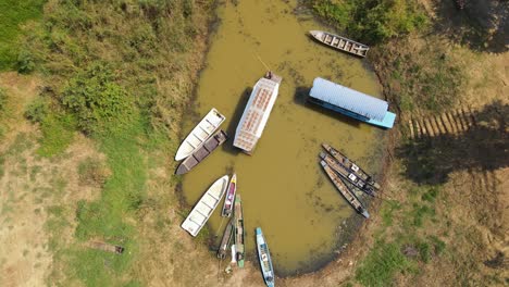 Aufschlussreiche-Luftaufnahmen-Einer-Bootstour-In-Bueng-Boraphet,-Nakhon-Sawan,-Thailand,-Ein-Großes-Boot,-Das-Aus-Der-Station-Herausfährt-Und-Von-Einem-Mann-Mit-Einem-Langen-Stock-Geschoben-Wird