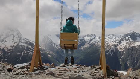 woman goes for a drive on a swing against a background of mountains. slow motion video.