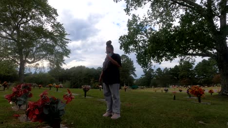 black woman with mask visiting gravesite of loved one during pandemic