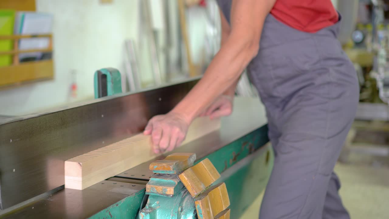 Worker planing wood on a jointer machine in a workshop