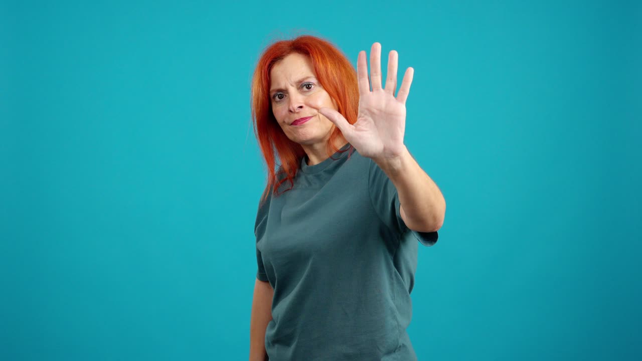 Woman with red hair making a stop gesture on a blue background