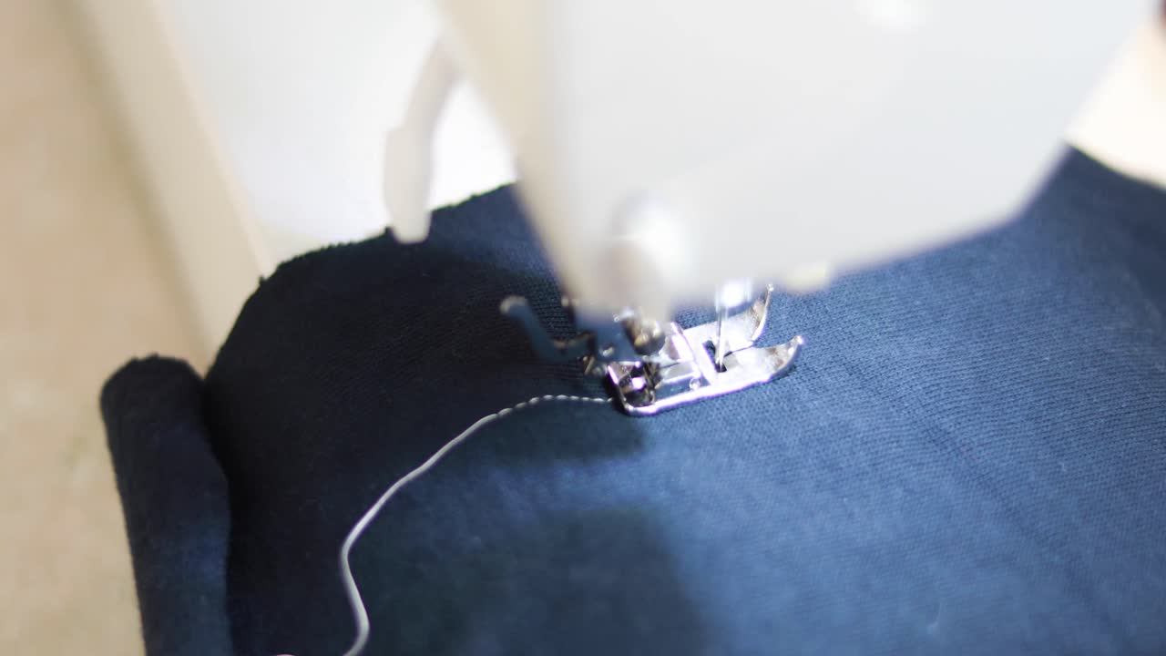 coser una línea blanca recta sobre tela azul con una máquina de coser