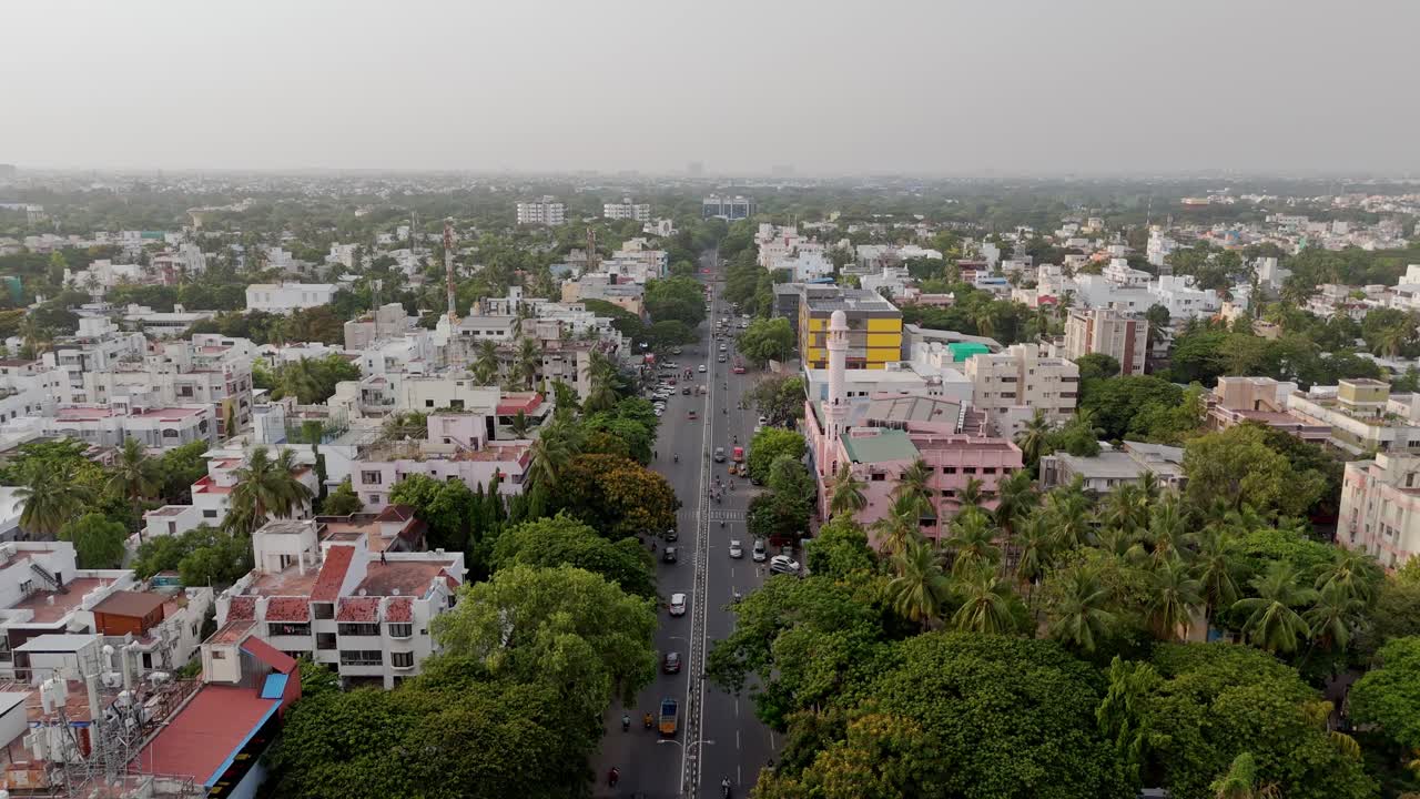 Aerial shot featuring bnusy roads wwith city surrounded in greenery in India.