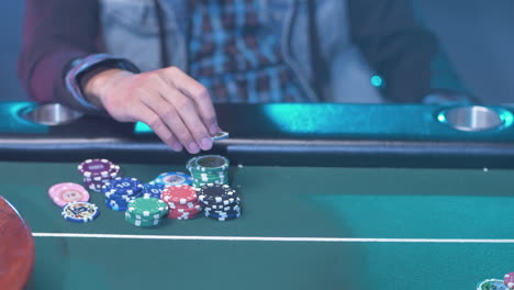 a professional poker player at the green table, moving his chips while waiting for his turn