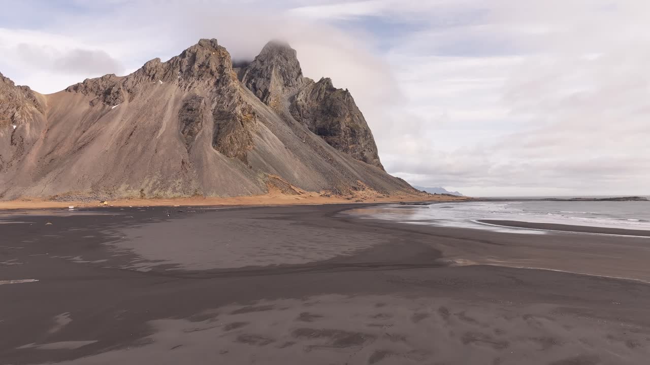 Rocky mountain peaks rise above a black sand beach in Stokksnes, Iceland