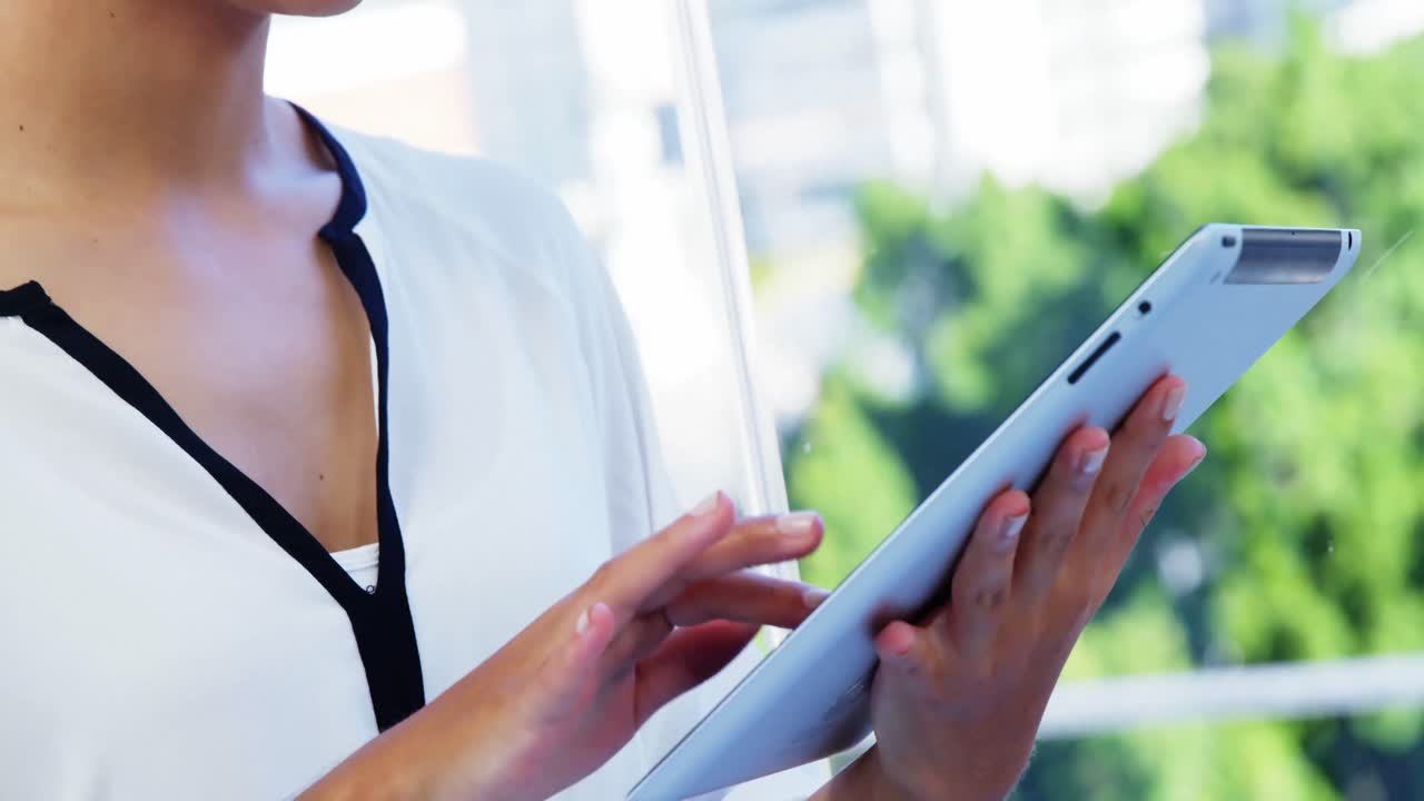 mujer usando una tableta frente a la ventana