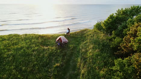 adventurous couple camping on a stunning baltic sea cliff, watching sunset glow