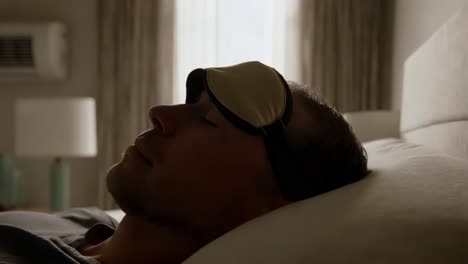 man sleeping in bed with sleep mask