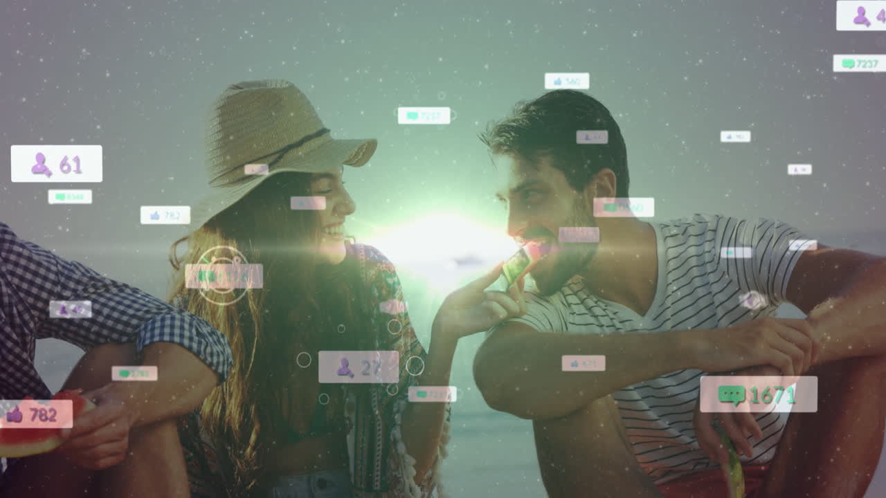 On beach, couple interacting with animation of social media icons floating around
