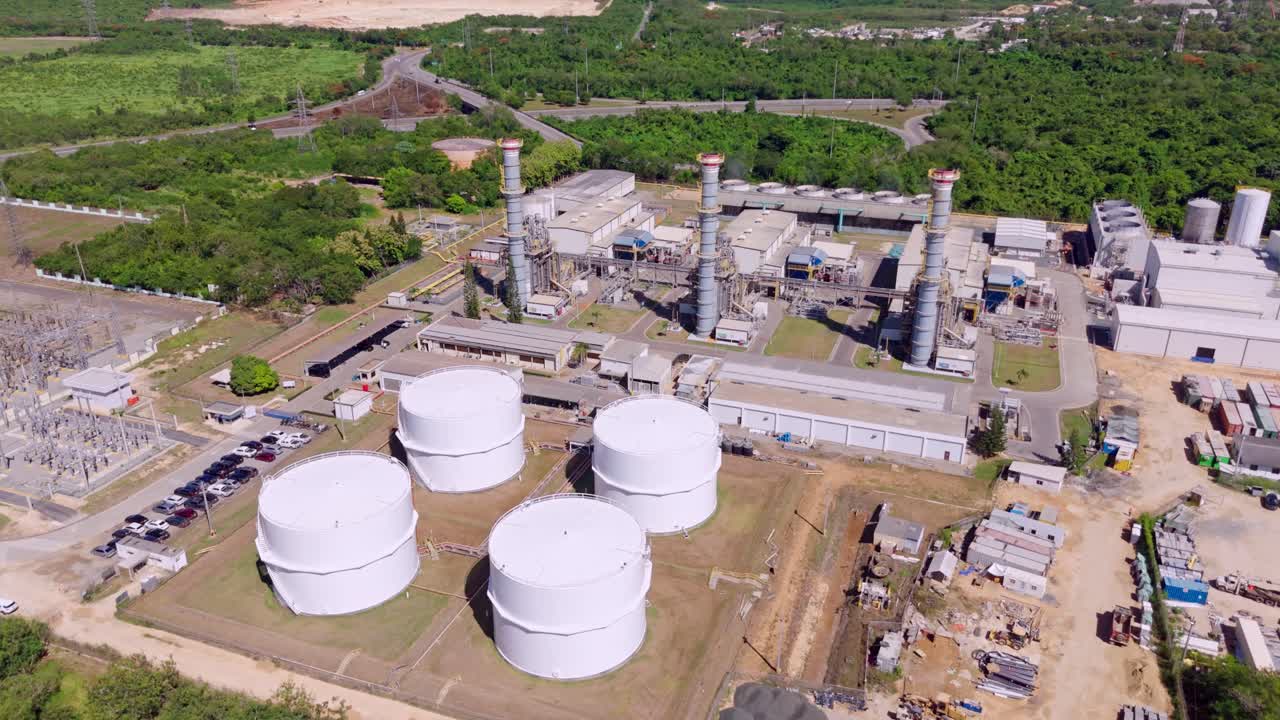 Aerial drone view of Energa 4 power generation facility, fuel storage tanks, substation, and smokestacks in San Pedro de Macoris, Dominican Republic