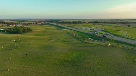 aerial view of highway cutting through lush fields at sunset