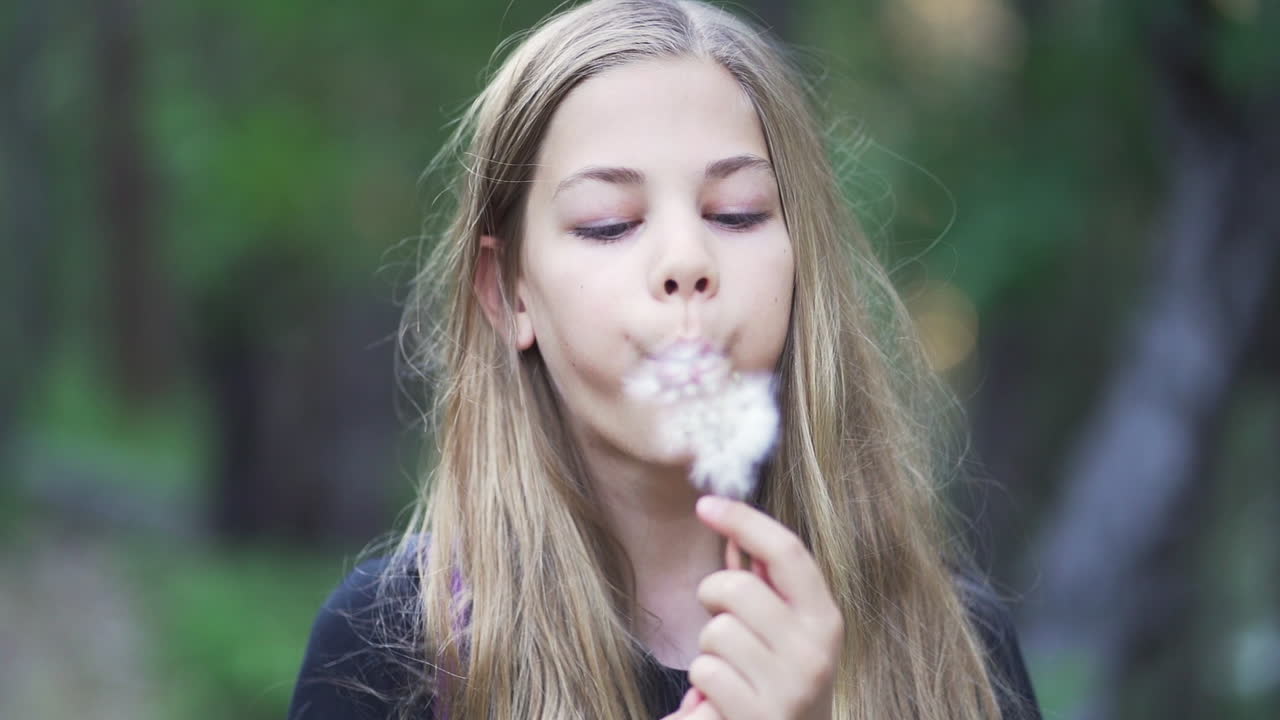 슬로우 모션, 정적 샷, 아름다운 금발 소녀가 민들레 머리를 불다