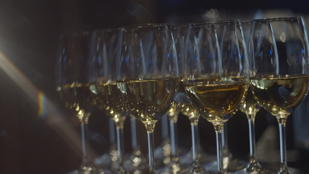 Primo piano di eleganti calici da vino pieni di vino bianco, isolati su sfondo nero