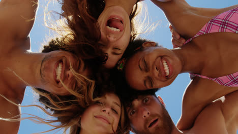 Young-friends-forming-huddle-at-beach-4k