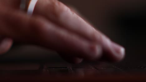 vista lateral de primer plano de las manos del hombre escribiendo en su computadora portátil retroiluminada por la pantalla