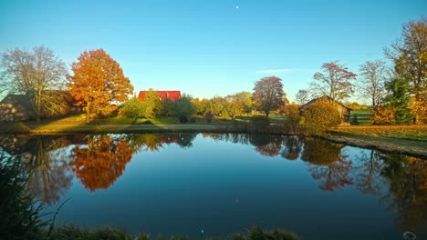 Toma-De-Tiempo-De-Casas-Al-Lado-De-Un-Lago-En-Frente-Desde-La-Mañana-Hasta-La-Noche-En-Un-Día-De-Otoño